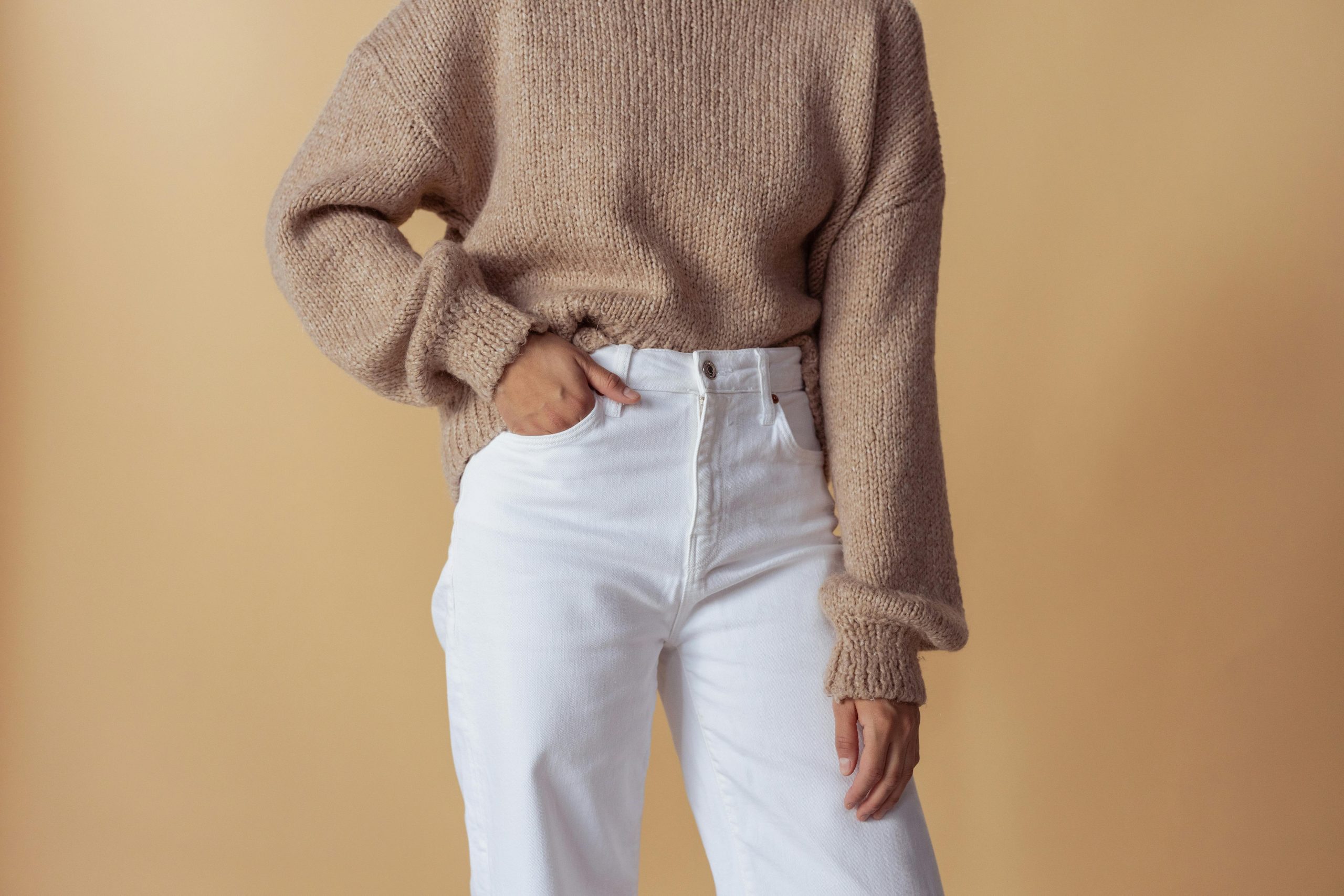woman wearing a beige sweater paired with white trousers